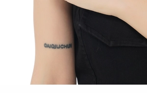 Detailed close-up of dark gray CAIQUCHUN letter tattoo sticker on arm inner side