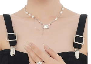 Detail of baroque pearl pendant necklace and matching ring on model in minimalist style