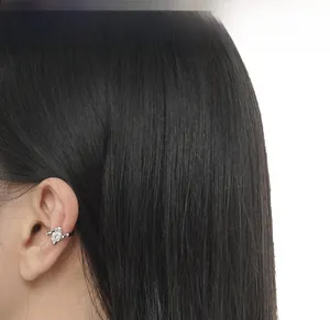 Detailed view of silver ear bone clip with heart-shaped zircon on female model