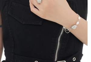 Detail of silver floral necklace and bracelet set with baroque pearls on model