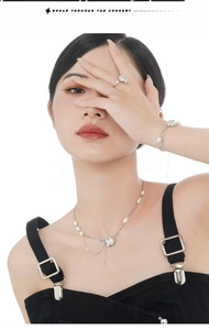 Detail view of baroque pearl necklace and bracelet with silver floral pendant on model