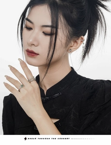 Close-up of bamboo-textured silver rings and green bead earrings on a model in qipao