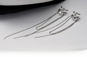 Détail macro de boucles d'oreilles en métal liquide avec longues chaînes à pompons argentés