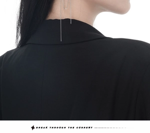 Gros plan de boucles d'oreilles à longues franges argentées sur un col de veste noir