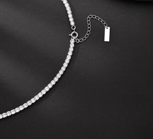 Detail of S925 silver tennis necklace featuring lobster clasp and extension chain on black