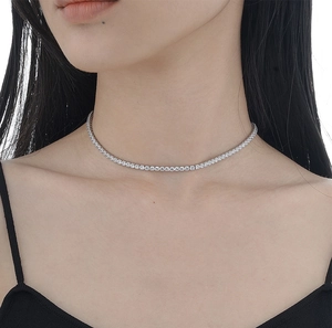 Close-up of a delicate silver tennis necklace with sparkling stones on a model