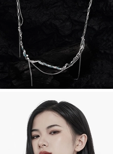 Détail d'un collier argenté multicouche avec des touches bleu menthe sur fond noir