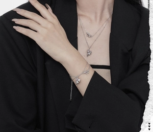 Detail of double-layer silver heart necklace and bracelet with zircons on model