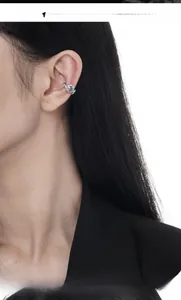 Macro detail of silver thorn-textured ear cuff with a square blue zircon on model