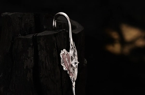 Macro detail of silver heart stud earring with pink enamel and square cubic zirconia