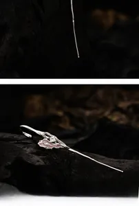 Detailed view of silver hair pin with delicate metal leaves and sparkling crystal center
