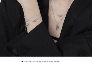 Dettaglio di collane e bracciali a cuore in argento a strati su un blazer nero