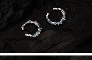 Macro shot of silver coral blue ear cuffs with irregular lava texture on charcoal background