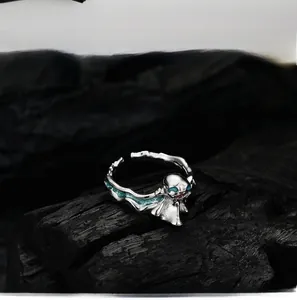 Macro shot of silver ghost ring with teal enamel on dark charred wood background