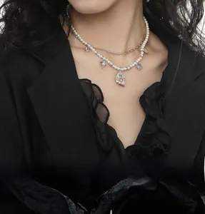 Close-up of layered pearl and silver necklace with colorful crystal charms and relief pendant
