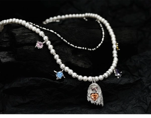 Macro shot of pearl necklace with colored gemstones and silver ghost heart pendant