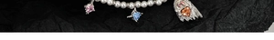 Detail of pearl necklace with pink square, blue star, and silver ghost charm pendants