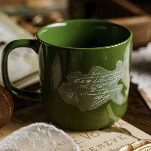 Vintage-Keramikbecher in Dunkelgrün mit weißem Schriftmuster auf rustikalem Grund