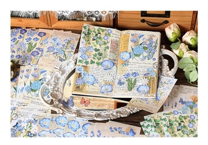 Vintage blue floral scrapbooking stickers with butterflies and script on wooden desk