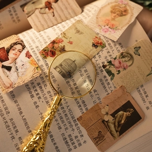 Lupa vintage de metal dorado con mango grabado sobre fondo de papel antiguo clásico