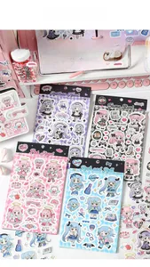 Flat lay of anime girl deco stickers on a desk with a pink keyboard and stationery