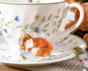 Close-up of cute crown cat PET sticker applied on a white floral ceramic cup