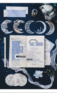 Detail of moon and star themed junk journal stickers with intricate lace cutouts in blue