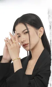 Close-up of gold necklace, earrings and ring set with pink gemstones on female model