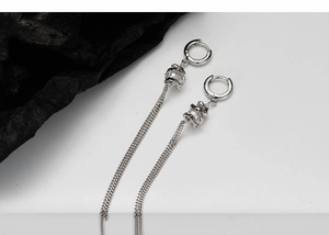 Close-up of elegant silver tassel earrings with white pearl inlay and metal chain fringe