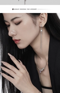 Detail of silver chain earrings with purple teardrop stones and pearls on model