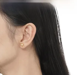 Close-up of golden irregular star stud earring with inlaid white opal on ear