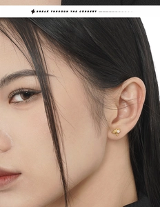 Macro shot of irregular gold star earrings with white opal stone on female model ear
