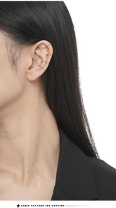 Détail de quatre bagues d'oreille en argent et or avec zircons portées sur l'oreille