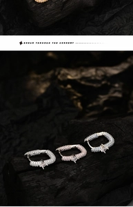 Macro shot of luxury S925 silver hoop earrings with zircon stones on dark wood background
