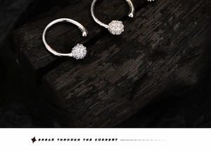 Gros plan d'une bague d'oreille en argent S925 avec boule en zircon sur bois sombre