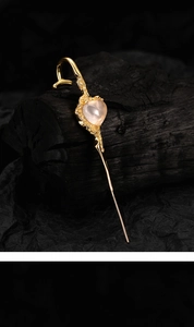 Detailaufnahme einer goldenen Herz-Haarnadel mit rosa Edelstein und organischer Textur-Optik