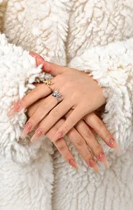 Detailed close-up of gold and silver elk head rings worn on model fingers