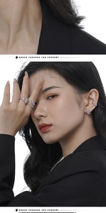 Detail shot of purple gemstone earring and ear cuff set worn by model in black suit