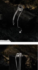 Detailed view of silver cuff earring with hollow chain fringe and white pearl accent