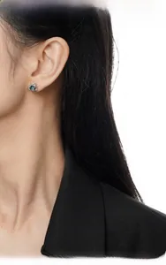 Close-up of small S925 sterling silver stud earring with a round teal gemstone on ear