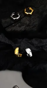 Détail macro de boucles d'oreilles hexagonales géométriques en or et argent sur bois sombre