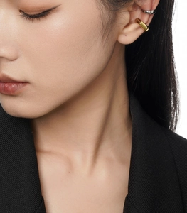Gros plan de manchettes d'oreilles minimalistes or et argent sur un mannequin en blazer noir