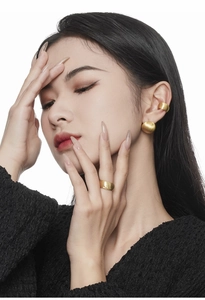 Detailed view of matte gold brushed earrings, ear cuff and ring set on female model
