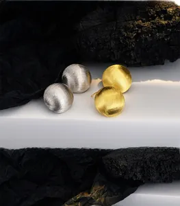 Detailed view of S925 silver stud earrings with brushed gold and silver hemispherical texture