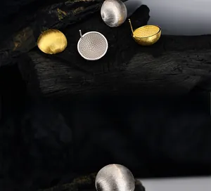 Detailed macro view of S925 silver stud earrings with brushed texture and honeycomb interior