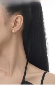 Detail eines Perlenohrsteckers mit goldener Lavatextur getragen von einem weiblichen Model