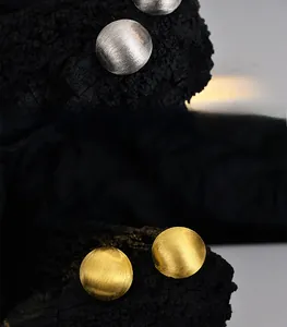 Macro detail of minimalist S925 sterling silver ball earrings with a brushed metal texture