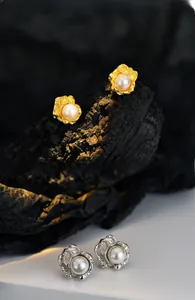 Details von floralen Perlenohrringen mit unregelmäßigen gold- und silberfarbenen Blüten