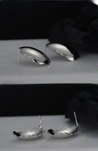 Macro detail of irregular wavy silver stud earrings with high-polish mirror finish