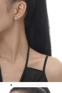 Nahaufnahme eleganter Perlenohrstecker mit Zirkonia-Akzenten an einem weiblichen Model